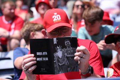 A fan wearing a number 20 hat reads the commemorative programme dedicated to Diogo Jota and Andre Silva ahead of the pre-season friendly match between Preston North End and Liverpool at Deepdale.