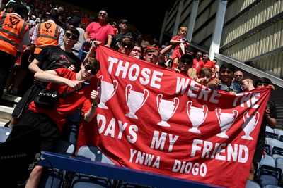 A fan of Liverpool holds up a banner which pays tribute to former Liverpool player Diogo Jota, which reads “Those were the days my friend YNWA Diogo” accompanied by six European Cups.